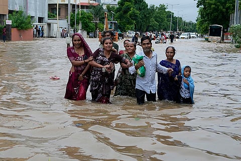A family wades through a flooded road in Ahmedabad